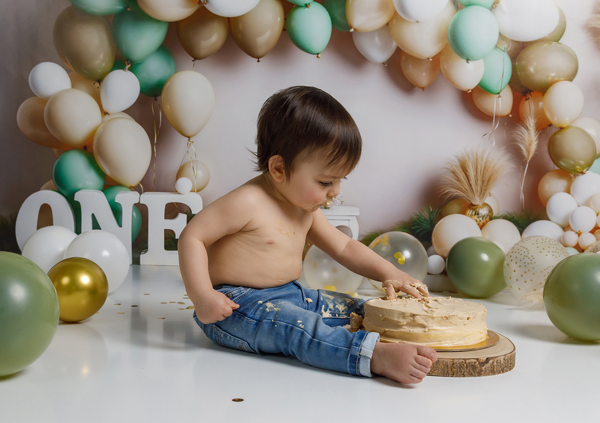 O menino Gabriel a olhar sorridente para a câmara enquanto esmaga o bolo. Imagem de excelência em foto coimbra para sessão de menino