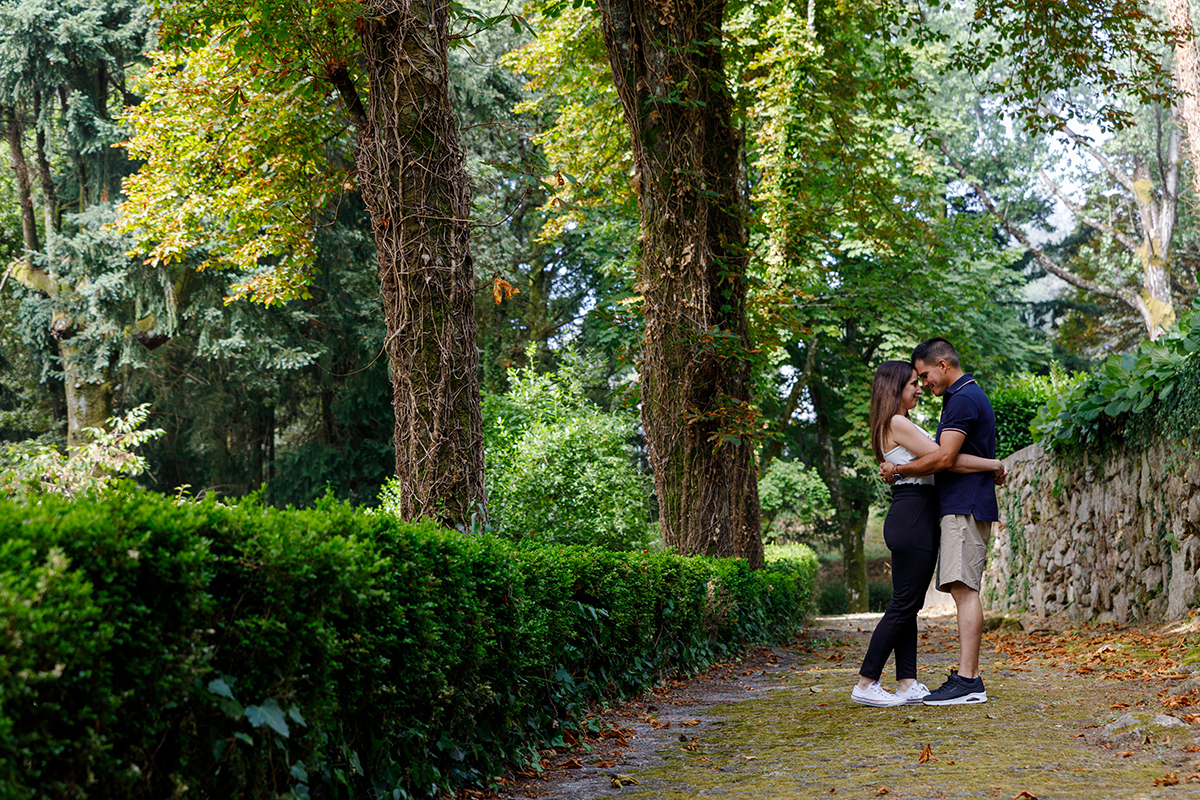 Casal abraçado em ambiente verde no Parque do Caramulo com elementos de granito, fotografia emocional por Fotocoimbra.