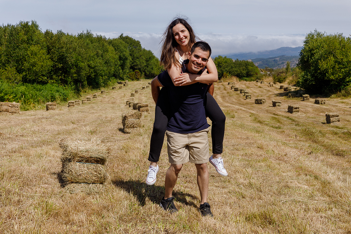 Noivos abraçados num prado com fardos de palha e vista ampla da serra, captado por fotógrafos de casamento Tondela e Viseu.