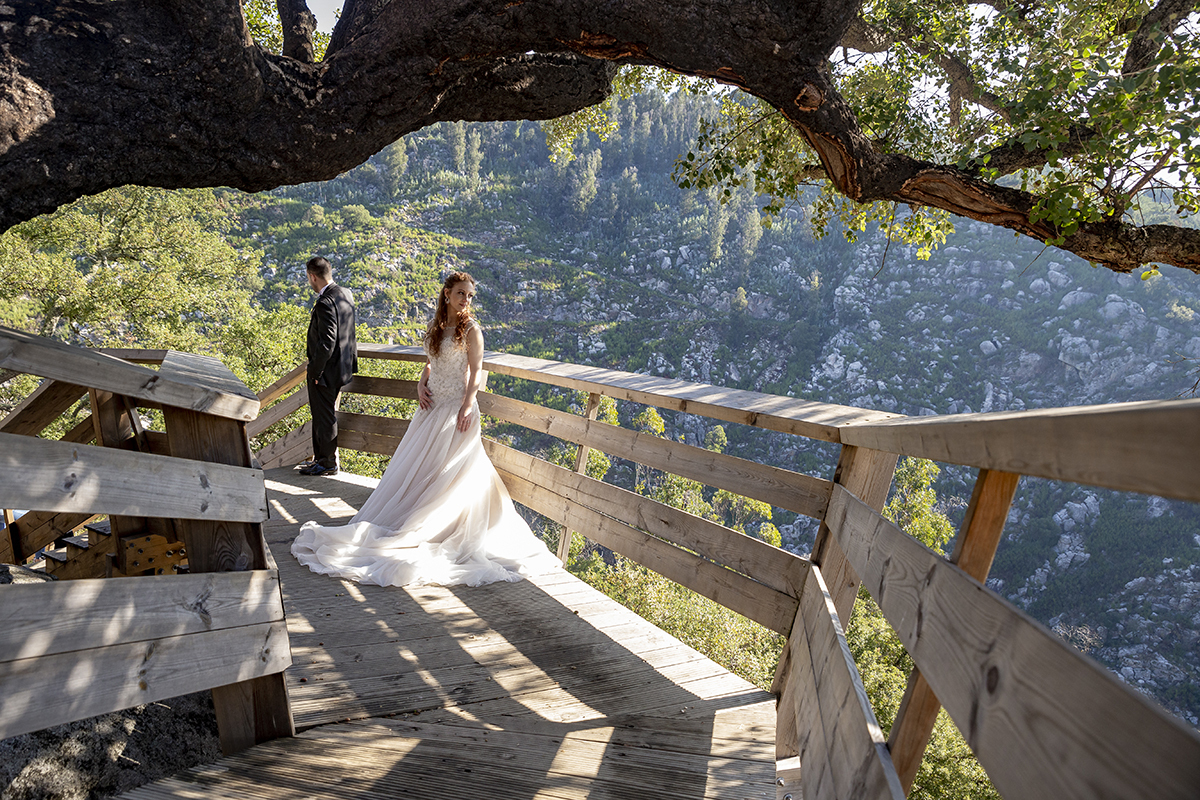 No mesmo cenário, Daniela mantém a pose sonhadora, agora ligeiramente de lado, com o olhar perdido no horizonte. Jorge, encostado ao corrimão, prepara-se para descer as escadas com calma, de costas para a lente.