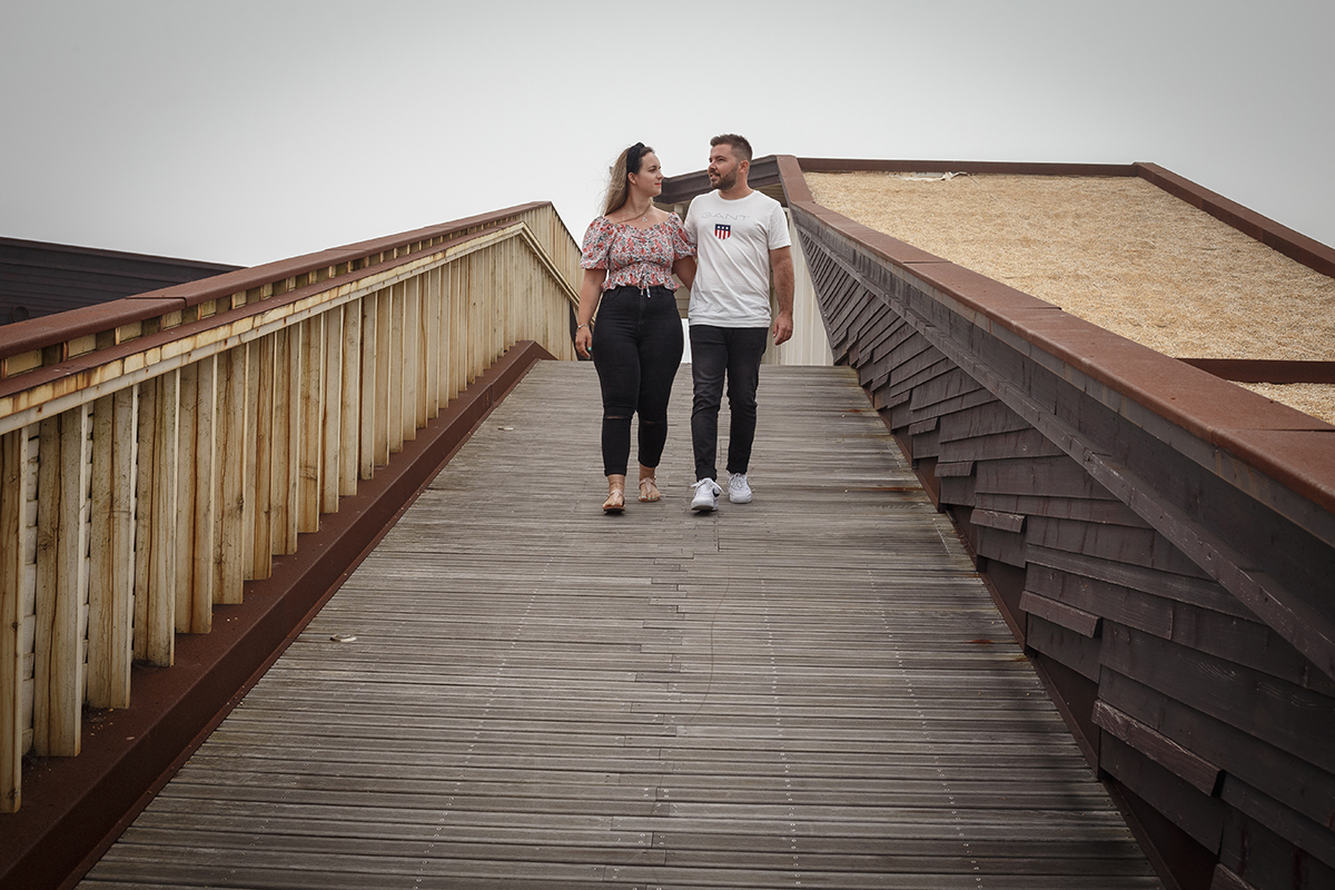 Caminhando lado a lado pelos passadiços, virados para a câmara, os dois olham-se com seriedade doce, partilhando um instante de cumplicidade onde o gesto é mais forte do que as palavras.