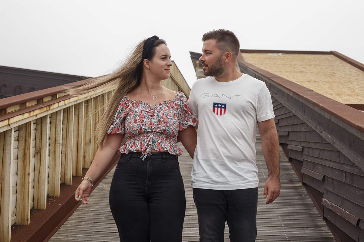 Num plano mais próximo, os dois surgem dos joelhos para cima com o vento a brincar com o cabelo de Marta, e os olhos deles cruzam-se num gesto profundo, enquanto caminham com as mãos nas costas um do outro, guardando o calor do toque.