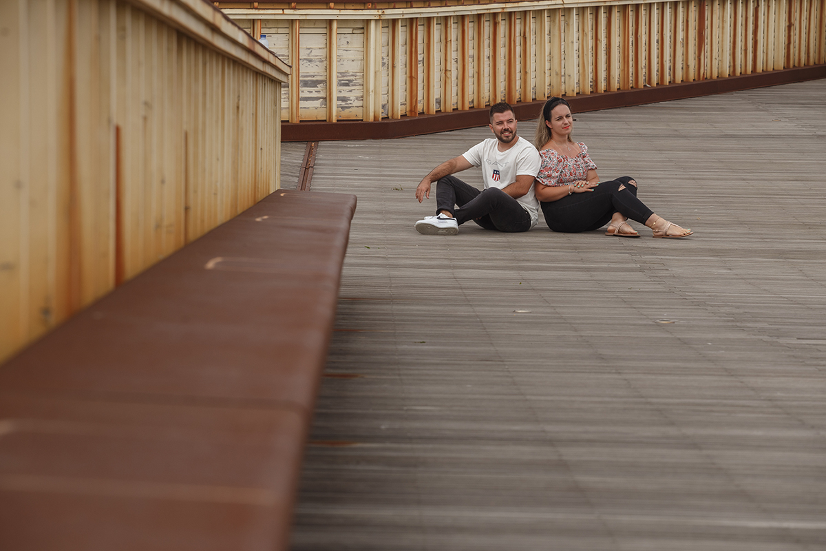 Sentados no passadiço, ligeiramente virados de costas, Marta e Ricardo mantêm as costas encostadas e os olhares voltados para a frente, sérios, como quem reflete em silêncio sobre o que já viveram e o que ainda está por vir.