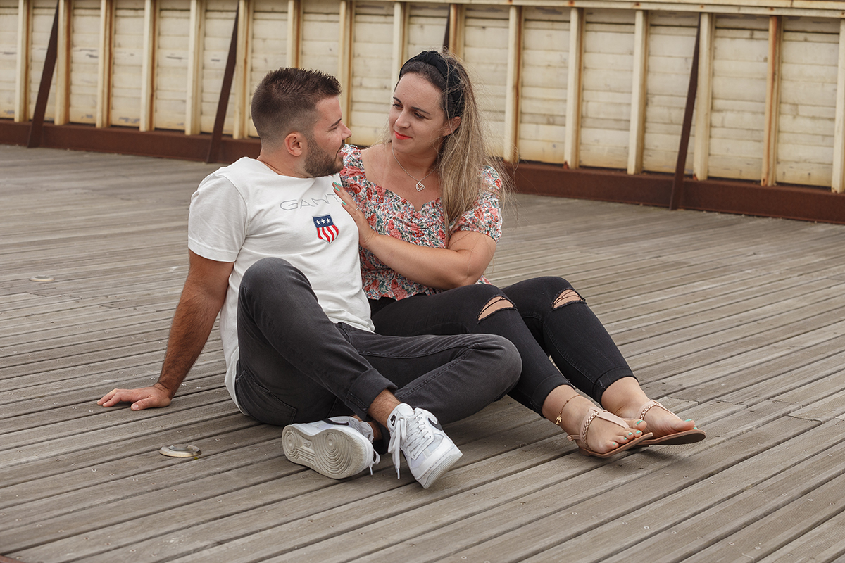 Num plano mais próximo, continuam sentados lado a lado nos passadiços, agora virados um para o outro com as mãos de Marta pousadas no peito de Ricardo, enquanto trocam olhares serenos, como quem reconhece ali a sua verdade.