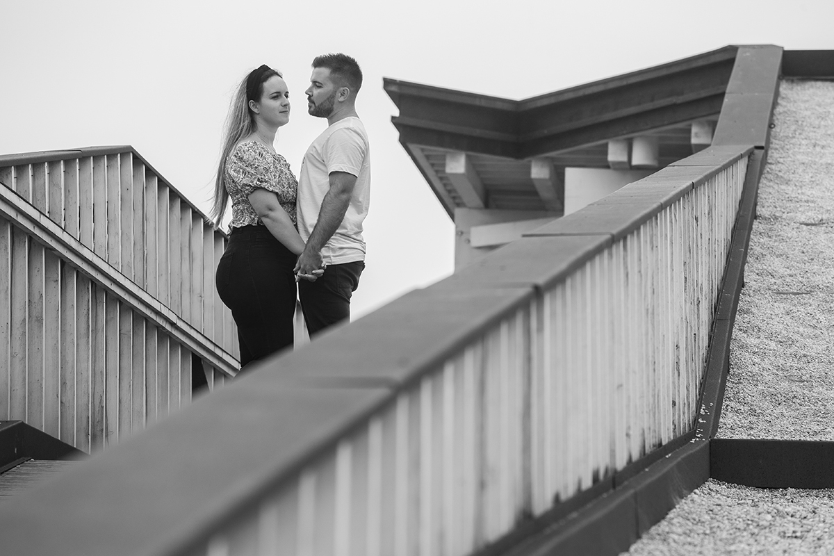 Em preto e branco e envoltos num corrimão que parece guardar o instante, os dois estão frente a frente de mãos dadas, Ricardo olha adiante enquanto Marta, ligeiramente virada, fixa o horizonte como quem sonha acordada.