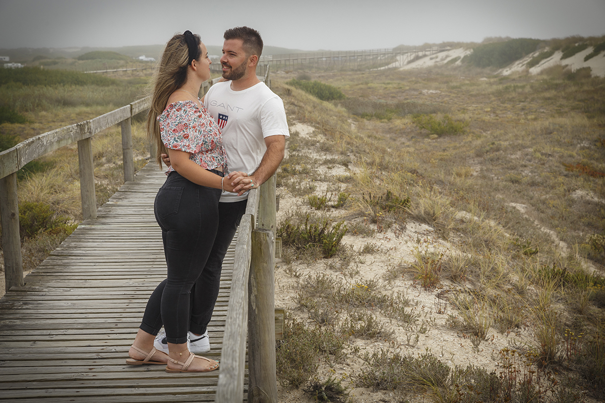Sentados nos passadiços, frente a frente com as pernas cruzadas, Ricardo segura as mãos de Marta entre as suas e sorri com a calma de quem se sente em casa, enquanto ela retribui o sorriso com um olhar rendido e doce.