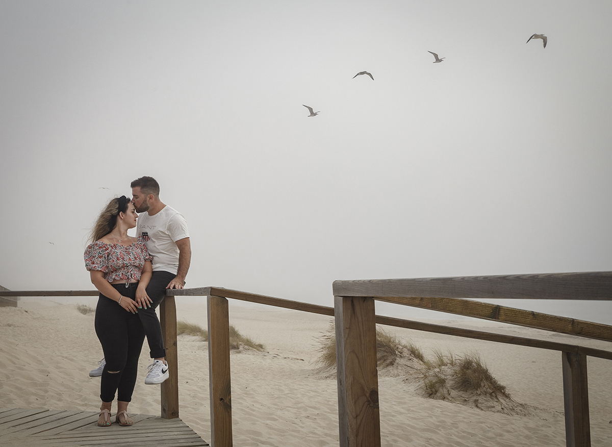Aqui vemos Ricardo sentado sobre o corrimão de madeira e à sua frente está Marta, com a cabeça virada para ele enquanto ele lhe dá um beijo na testa, num momento de ternura e paixão que fica na memória.