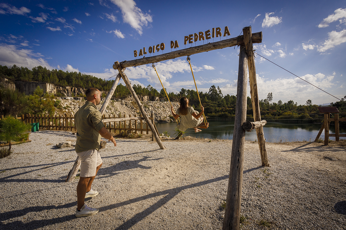 A cena mantém-se no baloiço encantado, mas agora Patrícia balança sozinha, com um sorriso a florescer no rosto enquanto Bruno, de pé atrás dela, a empurra com leveza. O gesto é cúmplice, sereno e divertido.