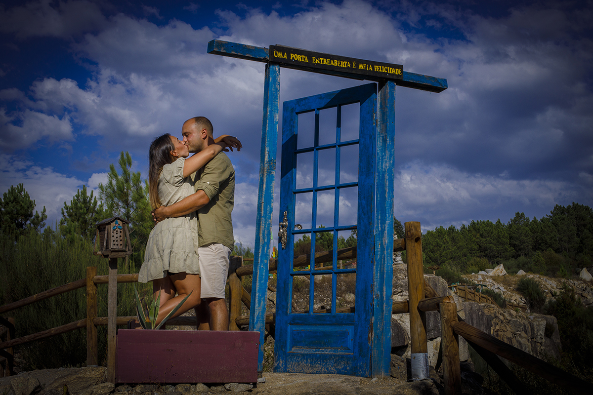 Ao pé de uma porta azul no meio de nenhures, ergue-se uma moldura mágica com letras que anunciam “UMA PORTA ENTREABERTA E MEIA FELICIDADE”. Lá dentro, os dois envolvem-se num beijo apaixonado, como se tivessem acabado de atravessar o limiar da sorte.