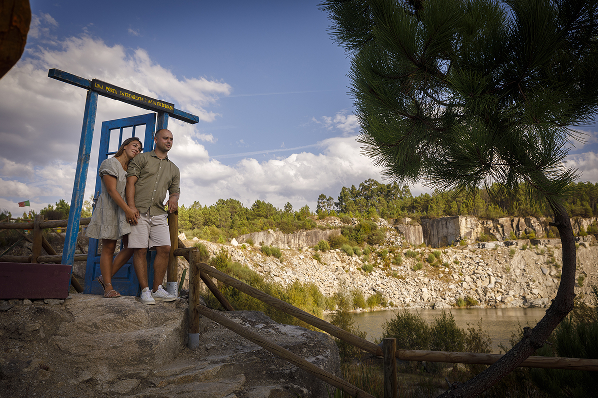 De novo junto à porta azul, agora num plano mais afastado, vemos os dois de mãos dadas, lado a lado, com Patrícia a apoiar suavemente a cabeça no ombro de Bruno. O horizonte alarga-se à frente deles como se o mundo inteiro estivesse por conquistar.