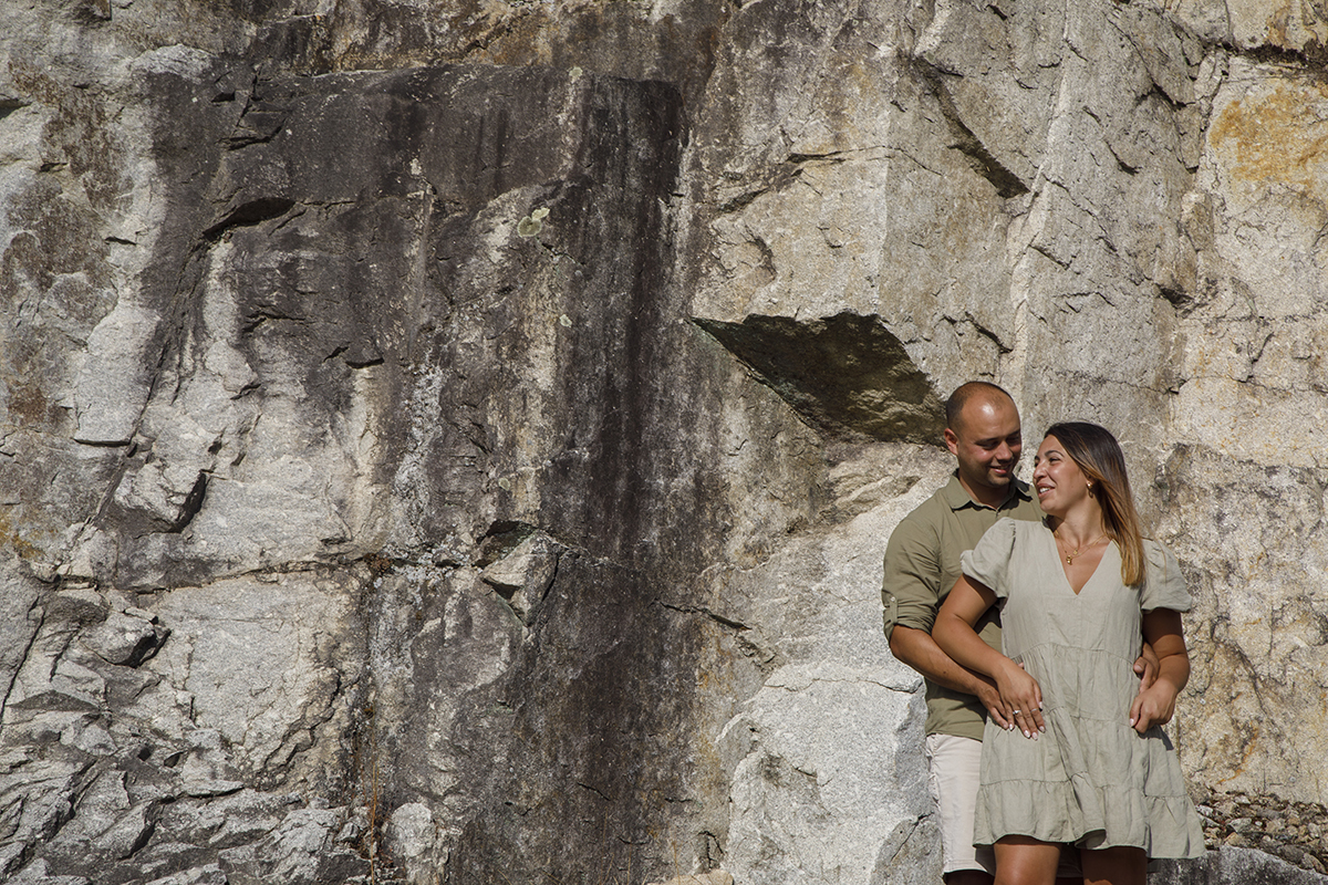Em plano mais próximo, Bruno encosta-se à rocha com Patrícia à sua frente, envolta nos braços dele. Ela segura-lhe as mãos com carinho e depois vira-se para ele com um olhar doce e apaixonado. É como se entre os dois houvesse apenas luz e silêncio.