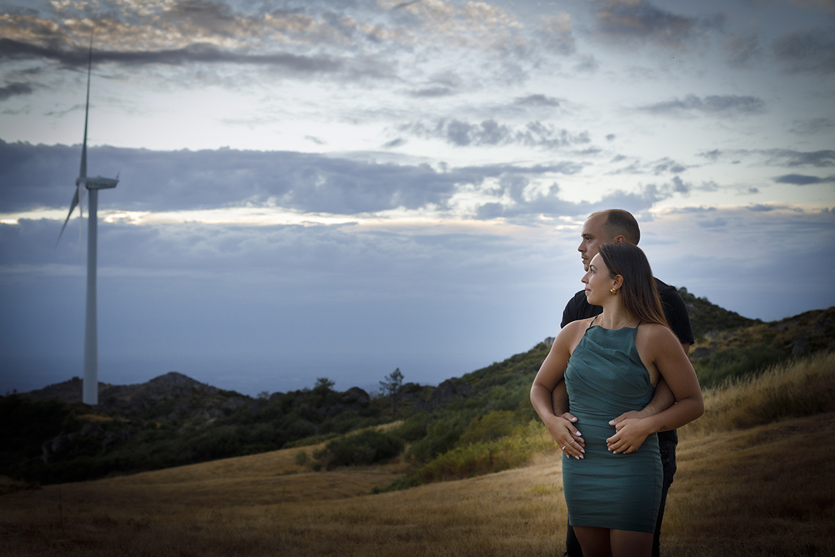 Num plano dos joelhos para cima, Bruno está atrás com as mãos pousadas na barriga de Patrícia, ela coloca as suas em cima das dele, ambos olhando para o lado com expressões sérias, mas cheias de cumplicidade e força.