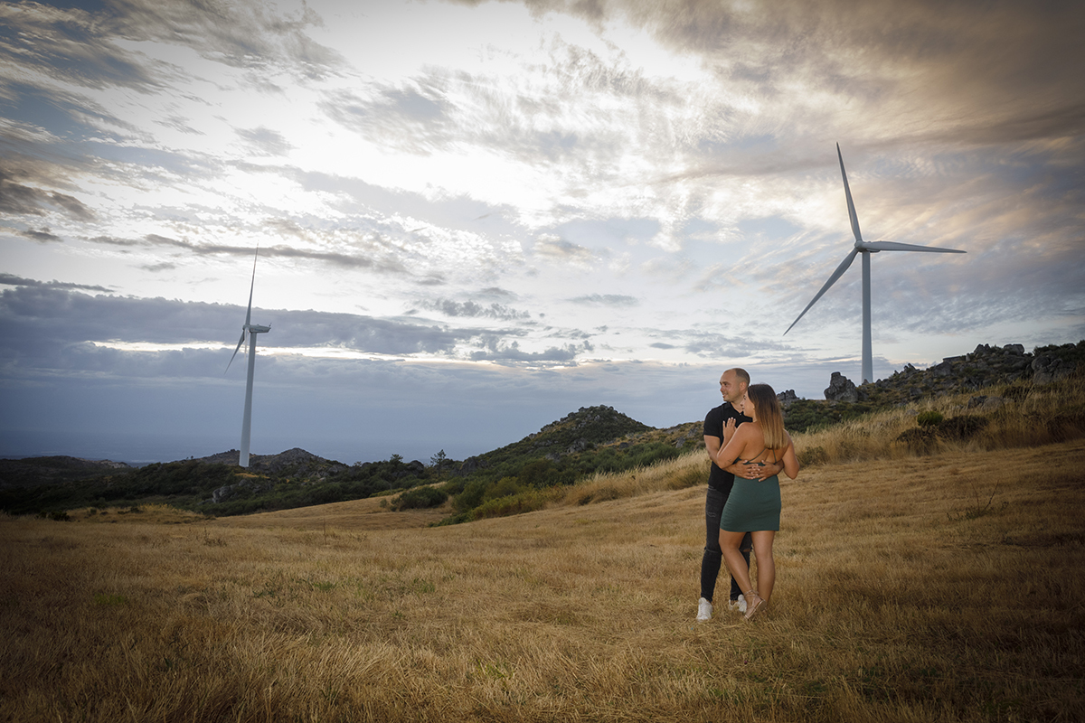 Com vinheta delicada, vemos os dois do lado direito da imagem, frente a frente, ele a abraçá-la enquanto ela pousa as mãos no peito dele. Ambos olham para a frente com sorrisos suaves, num cenário onde ventoinhas eólicas pontilham o céu e um campo.