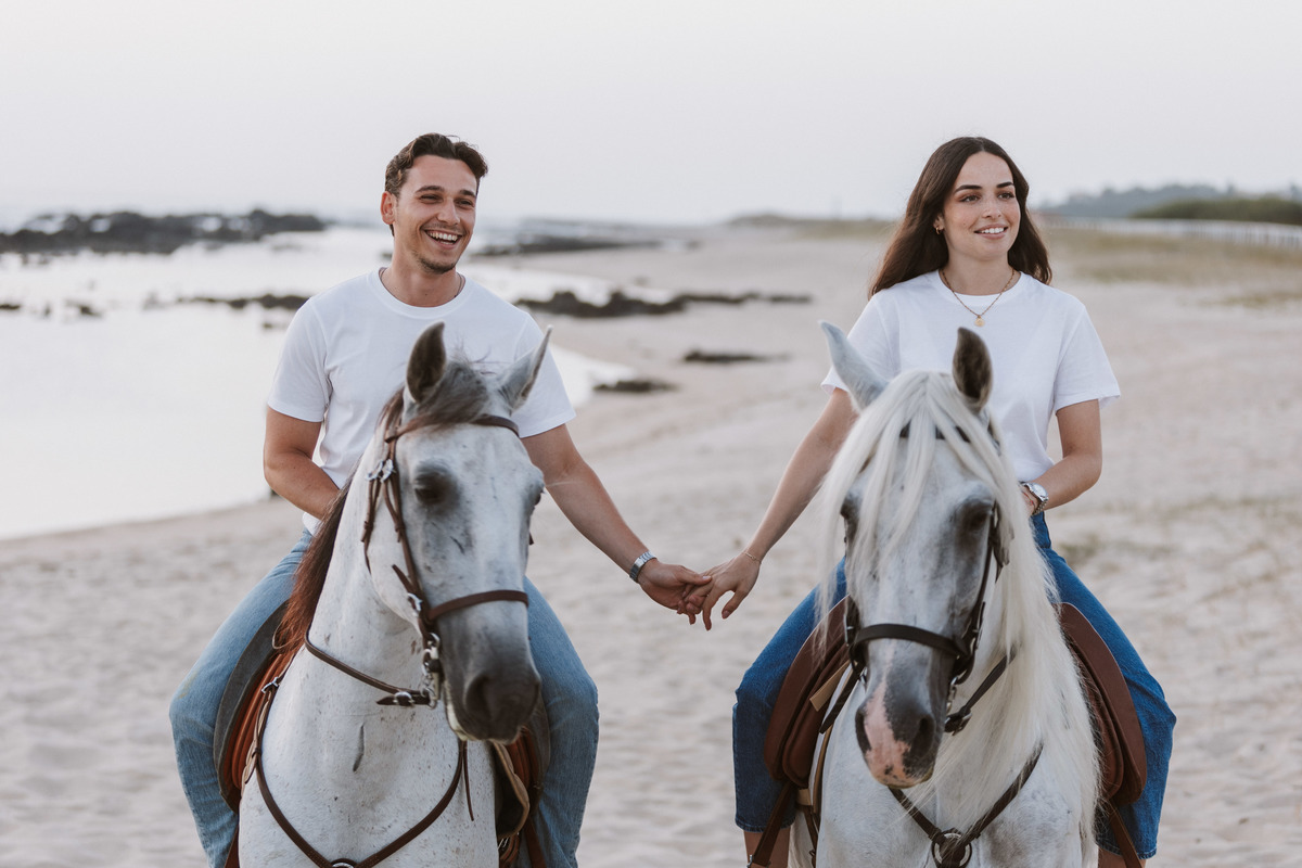 Retrato de casal em sessão de solteiros na praia, luz natural de pôr do sol.