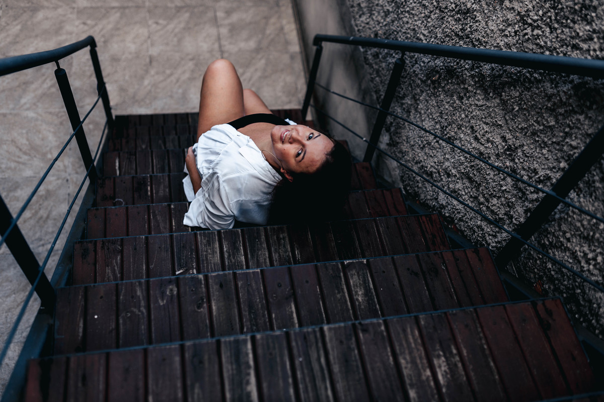 fotografia de mulher de camisa branca sentada na escada