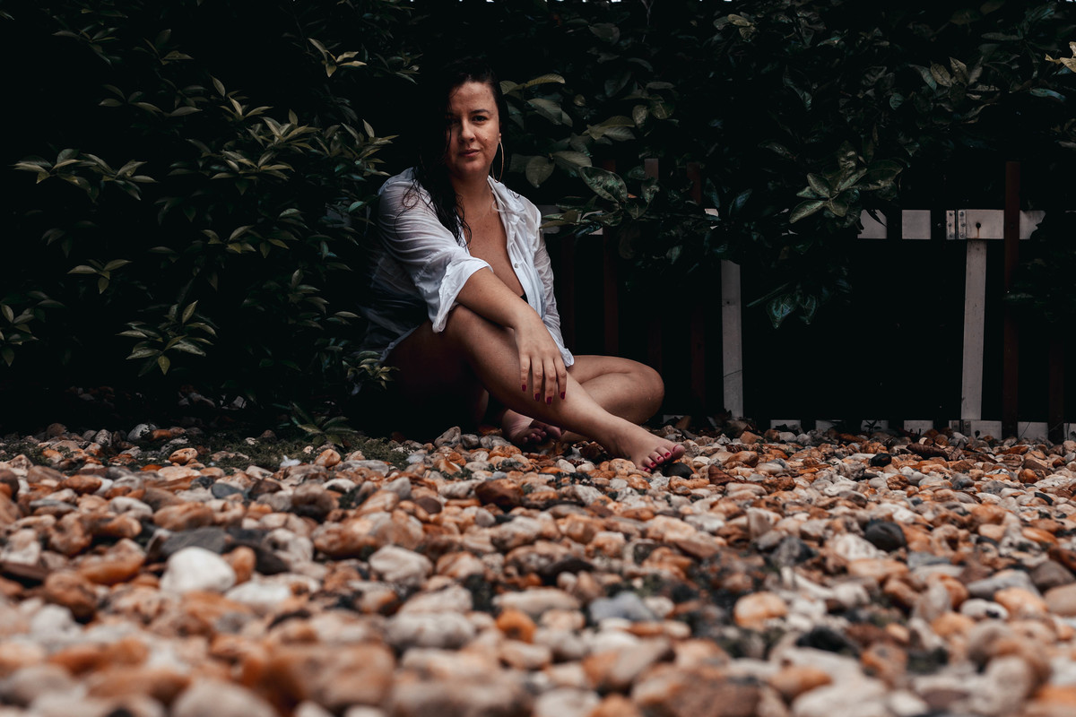 foto de mulher molhada de camisa branca sentada em jardim em Florianópolis 