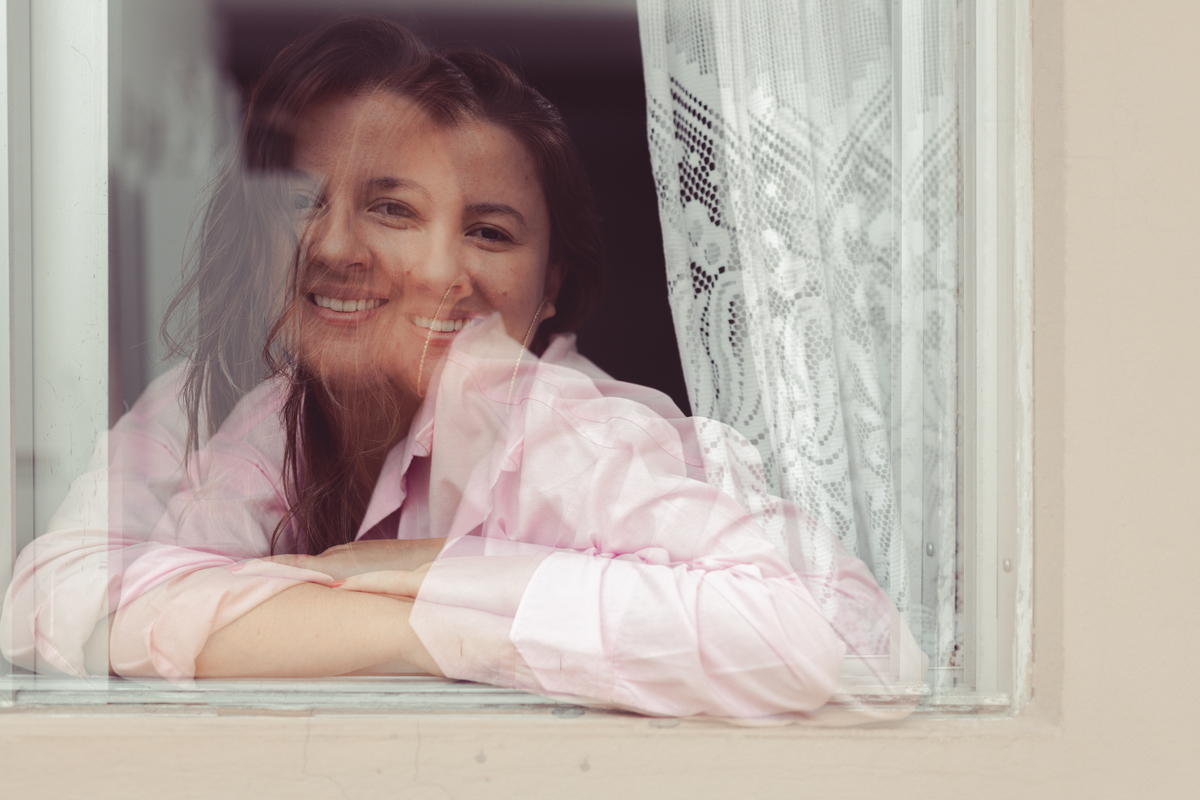 foto de mulher com camisa rosa apoiada na janela. foto com com sobreposição de a mesma imagem.