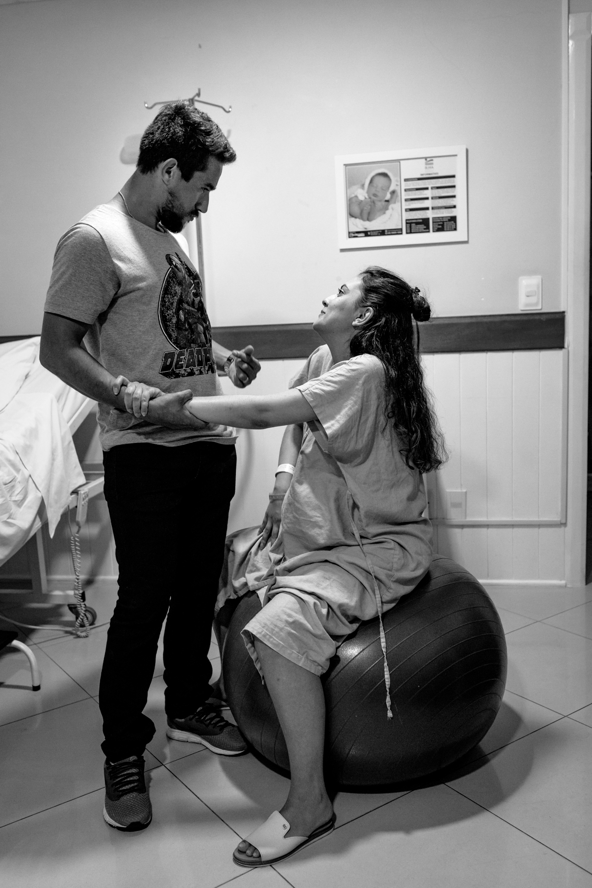 mulher grávida na bola de pilates brincando com o marido na maternidade