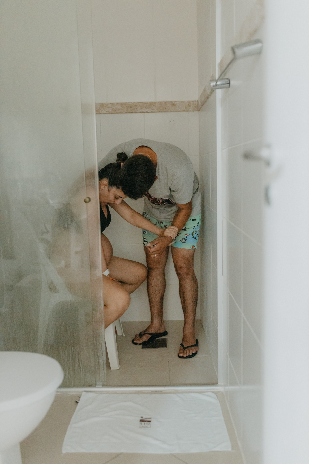 gestante sentada na cadeira no chuveiro da maternidade amparada pelo marido