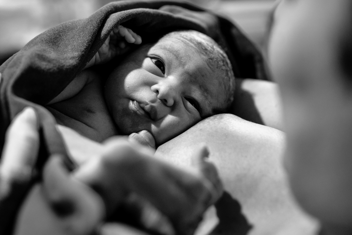 bebê recém nascido no colo da mãe olhando pra ela na maternidade em Florianópolis. Foto em preto e branco