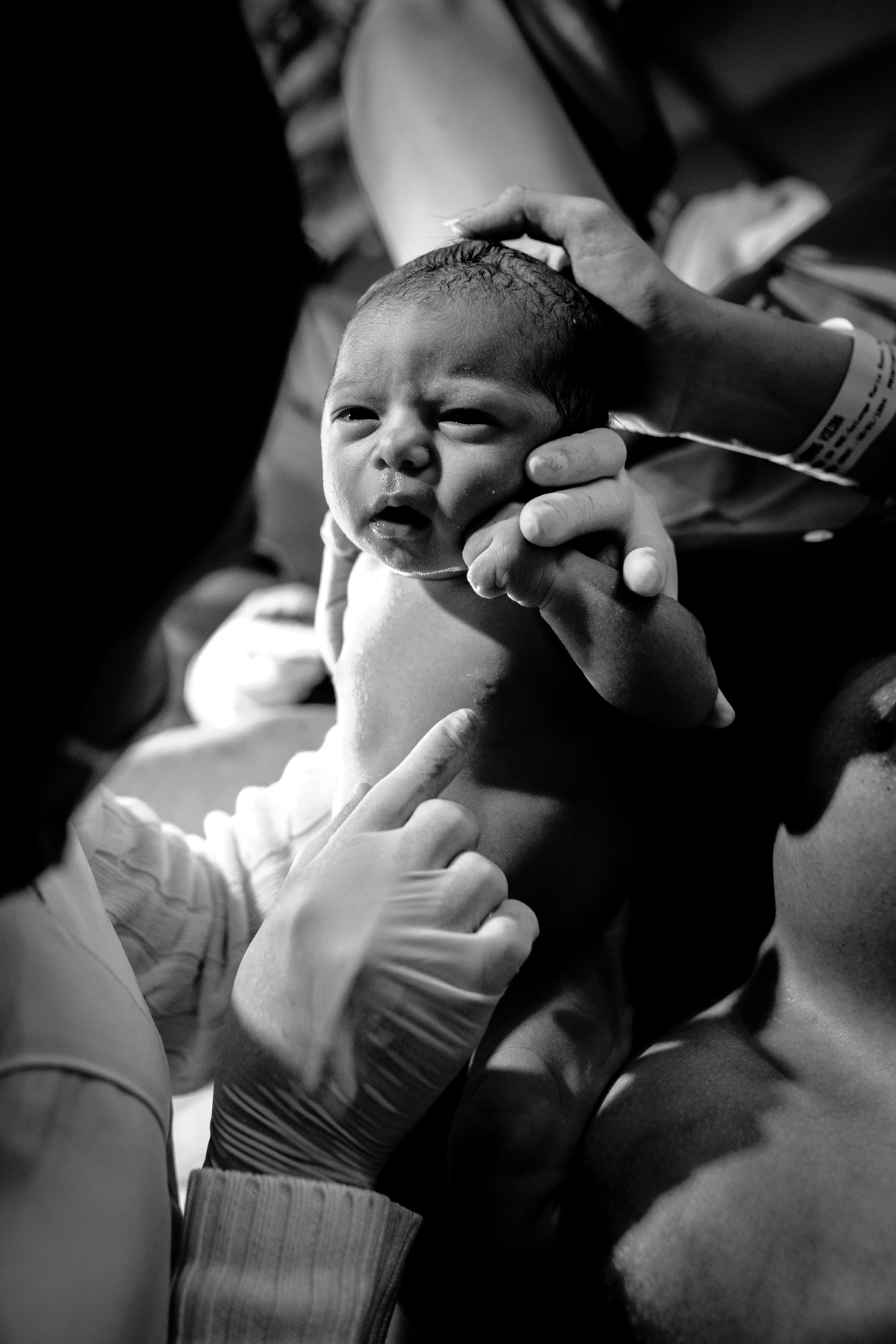 bebê recém nascido olhando para a enfermeira enquanto ela faz o exame nele na maternidade. foto em preto e branco