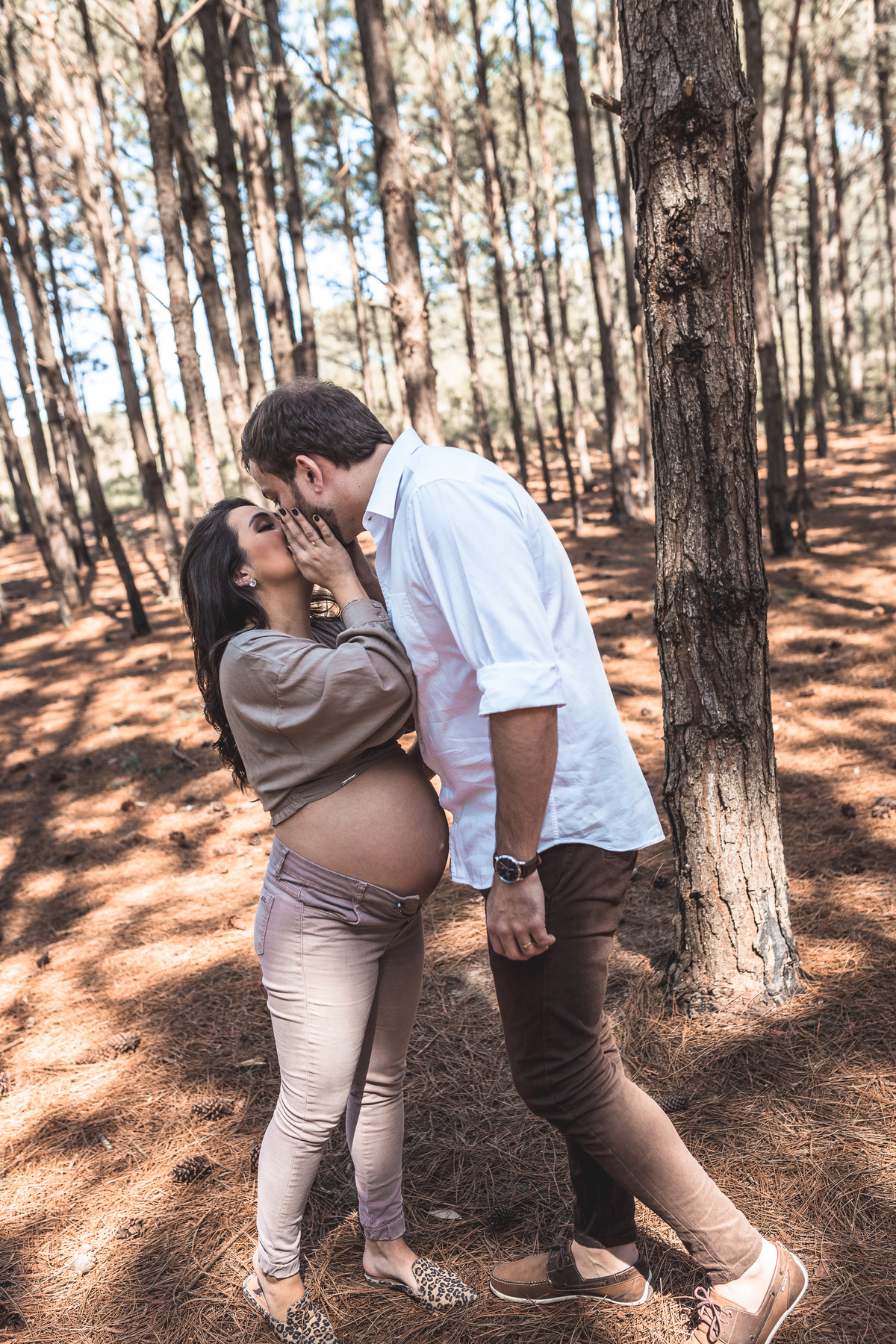 casal grávidos se beijando em um parque