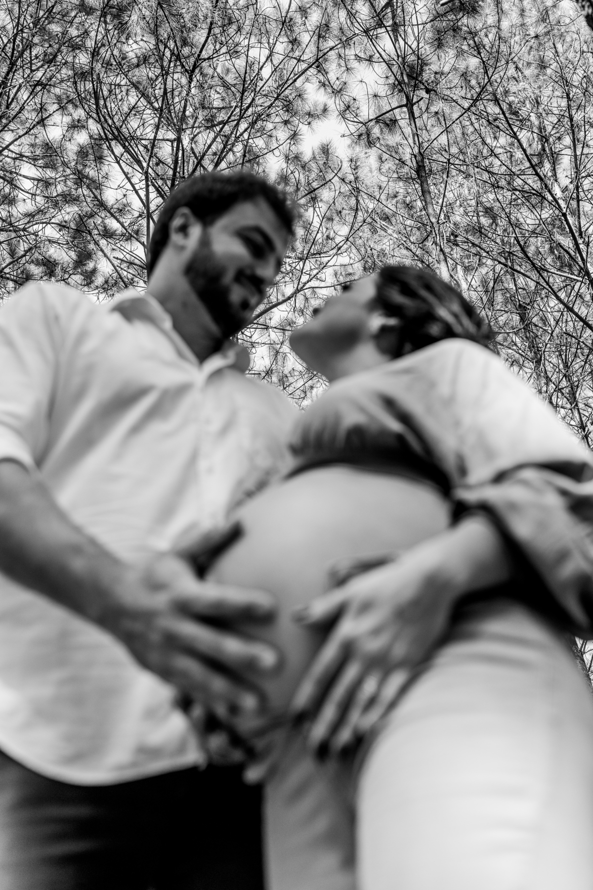 marido e mulher se olhando, marido com a mão na barriga da esposa grávida em preto e branco