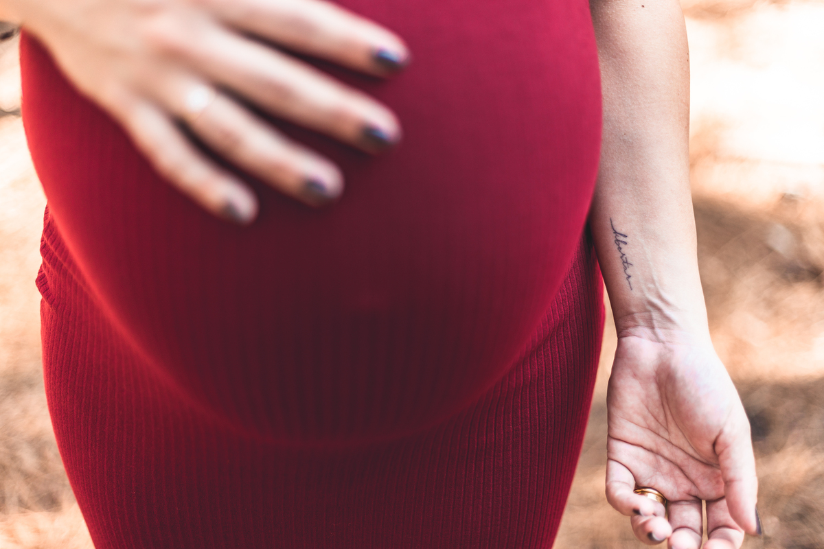 barriga de gestante e braço com tatuagem escrito 