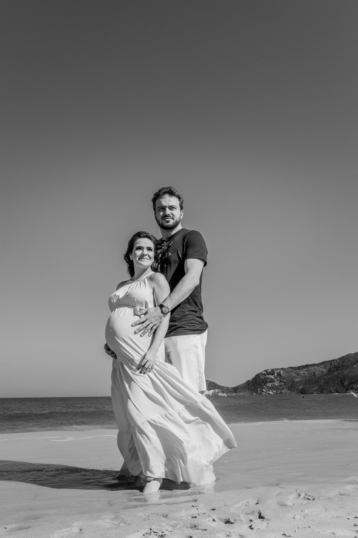 casal grávidos na praia olhando para o horizonte, foto em preto e branco