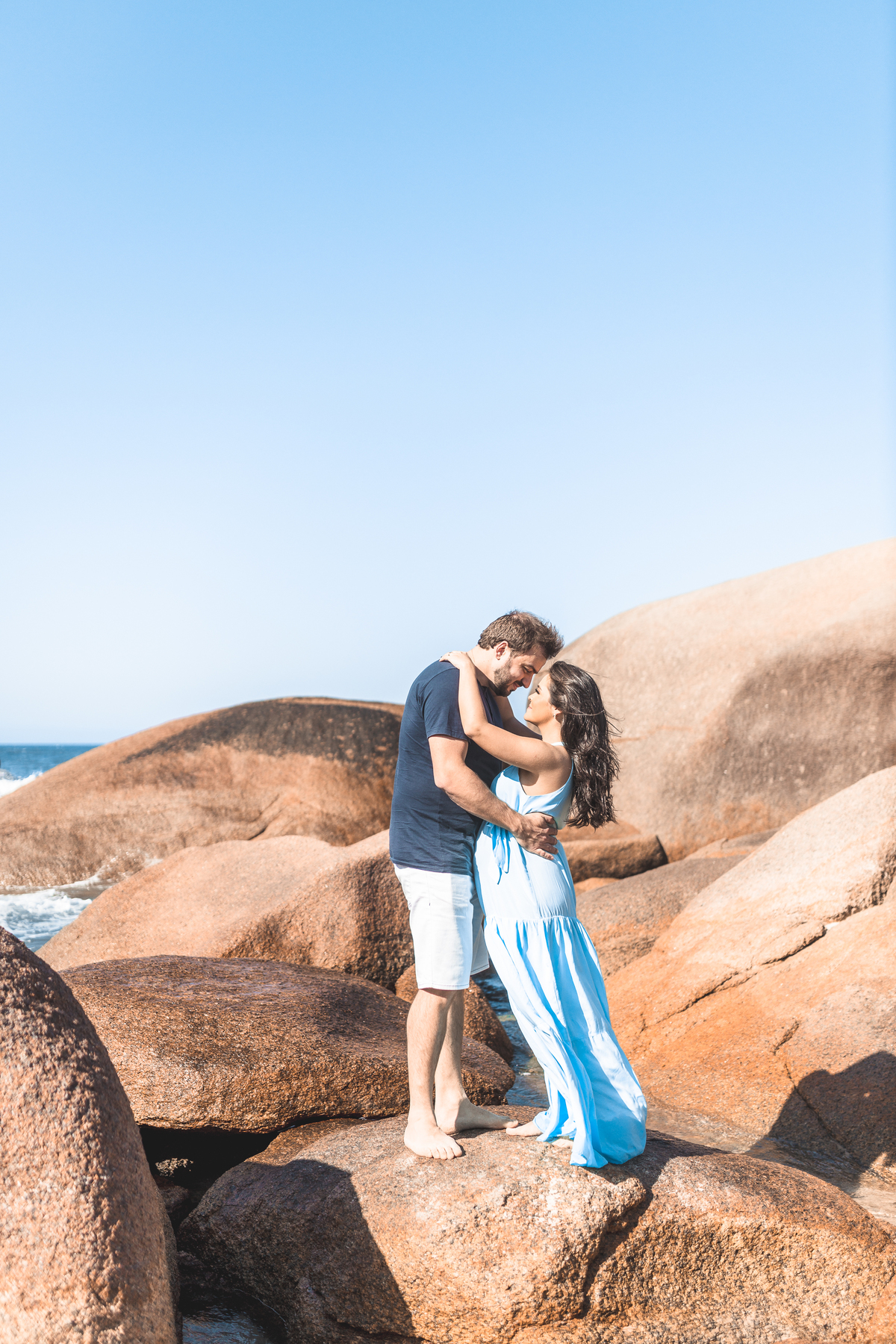 casal apaixonado abraçados nas pedras da praia de Florianópolis. Mulher gestante