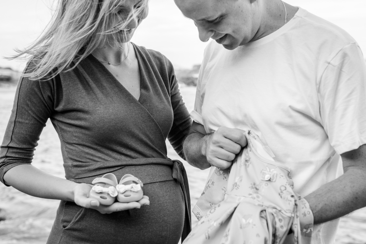 marido e esposa grávida com vestido e sapato da bebê que vai nascer. foto em preto e branco