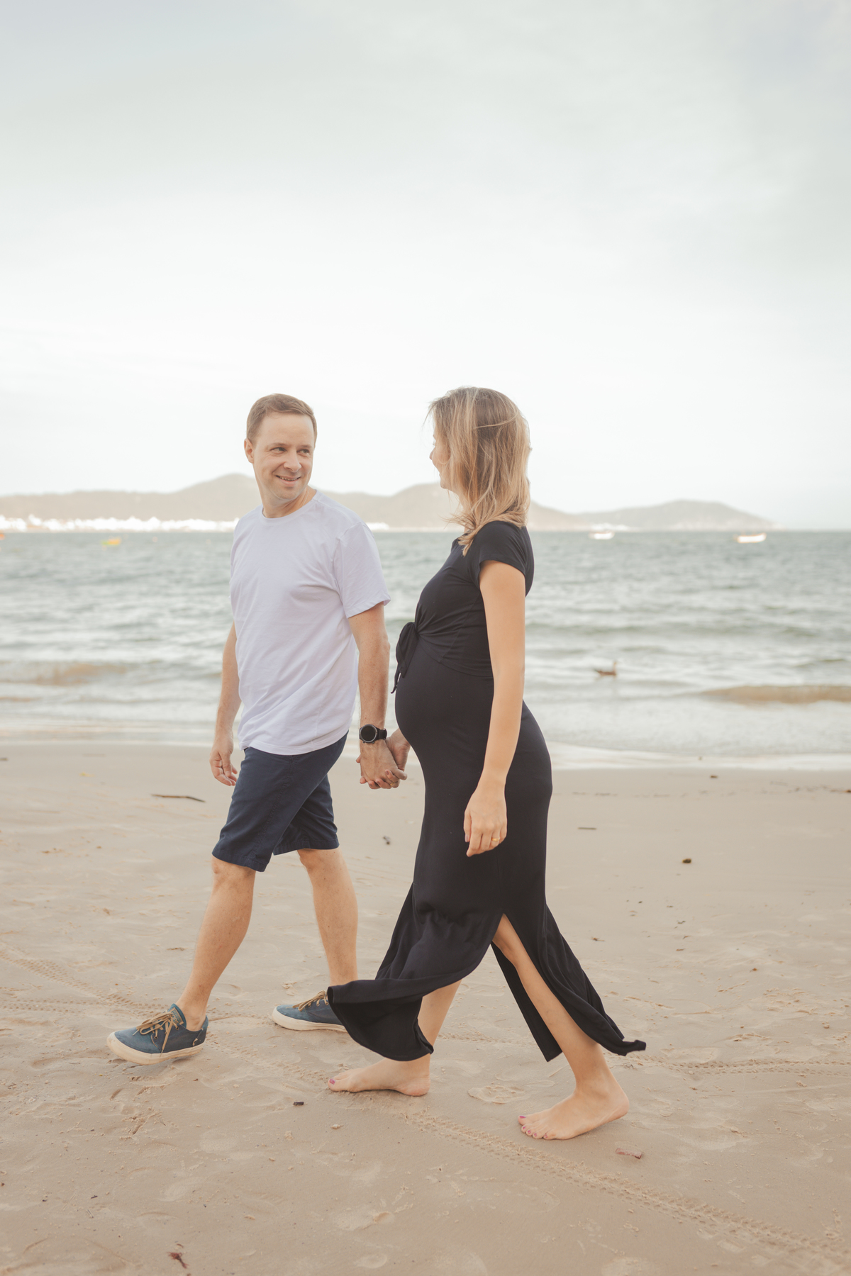 casal apaixonado andando na praia de Florianópolis. Mulher gestante 