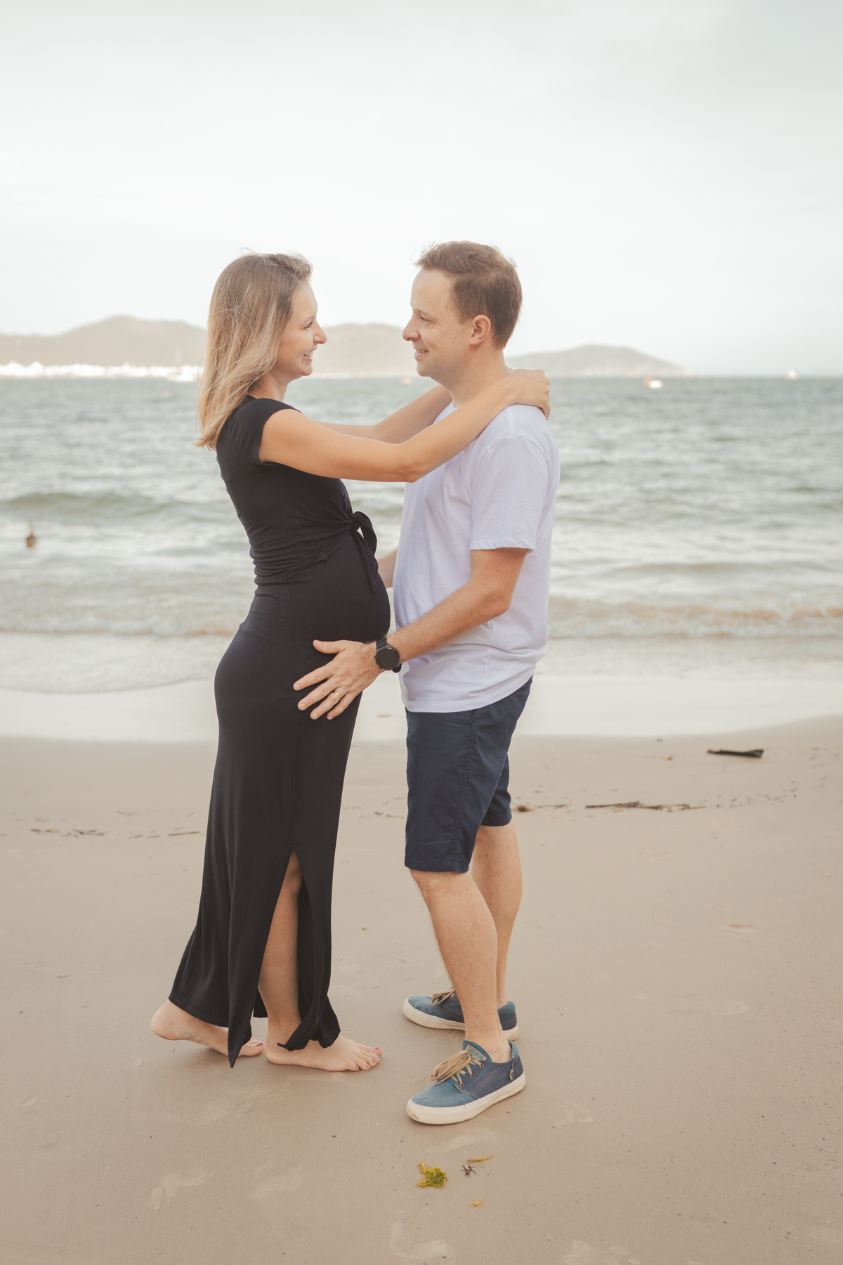 casal apaixonado se olhando na beira do mar em Florianópolis. gestante