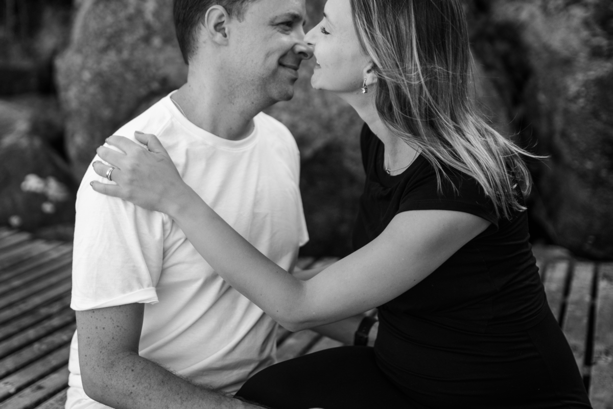 casal apaixonado quase se beijando sentados no trapiche da praia em Florianópolis