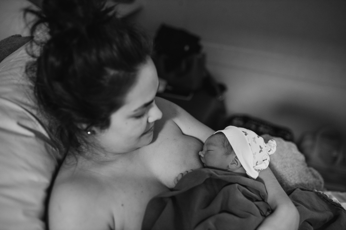 foto em preto e branco de bebê de toquinha no colo da mãe sendo amamentado