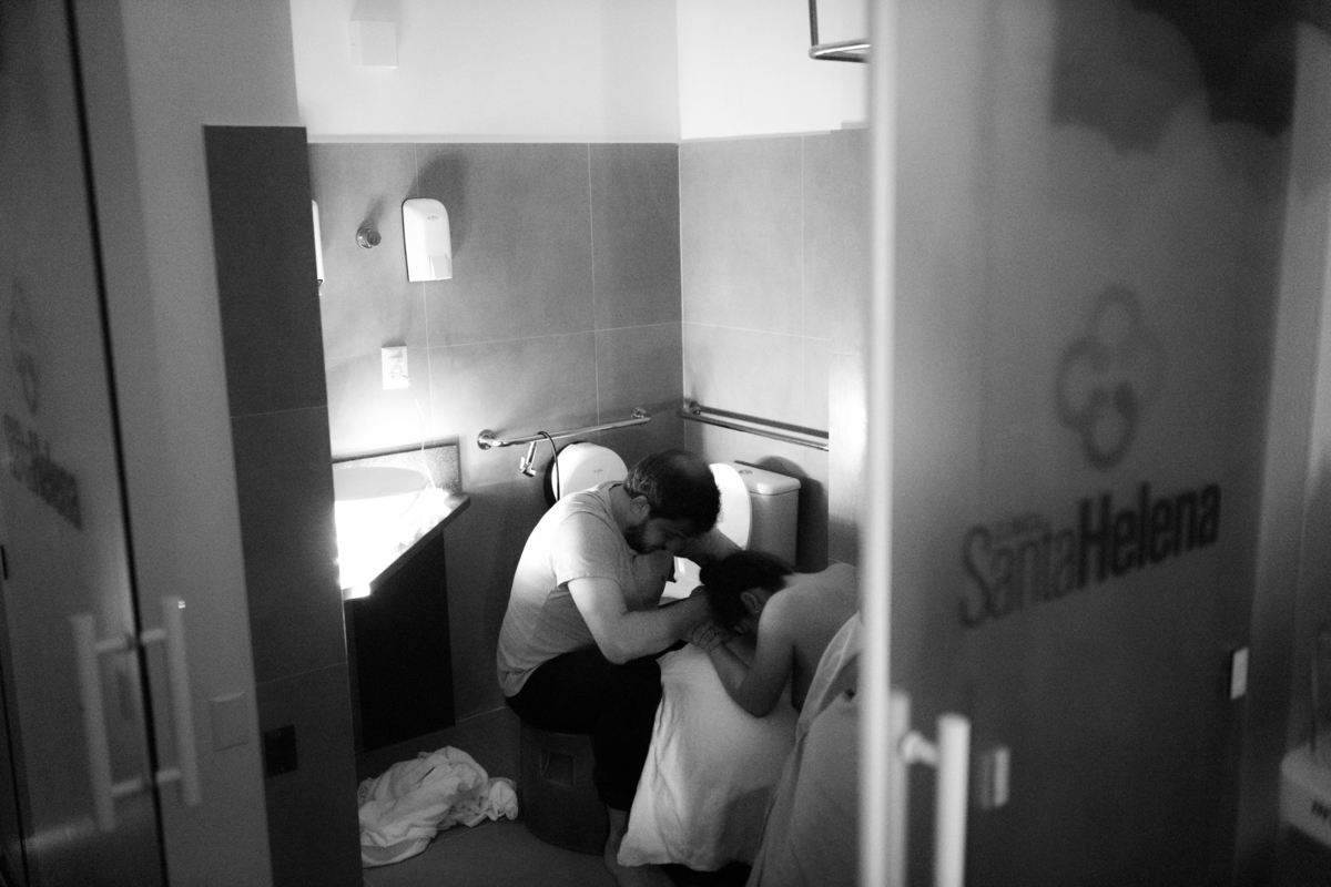 foto em preto e braco de gestante em chuveiro da maternidade recebendo suporte do marido