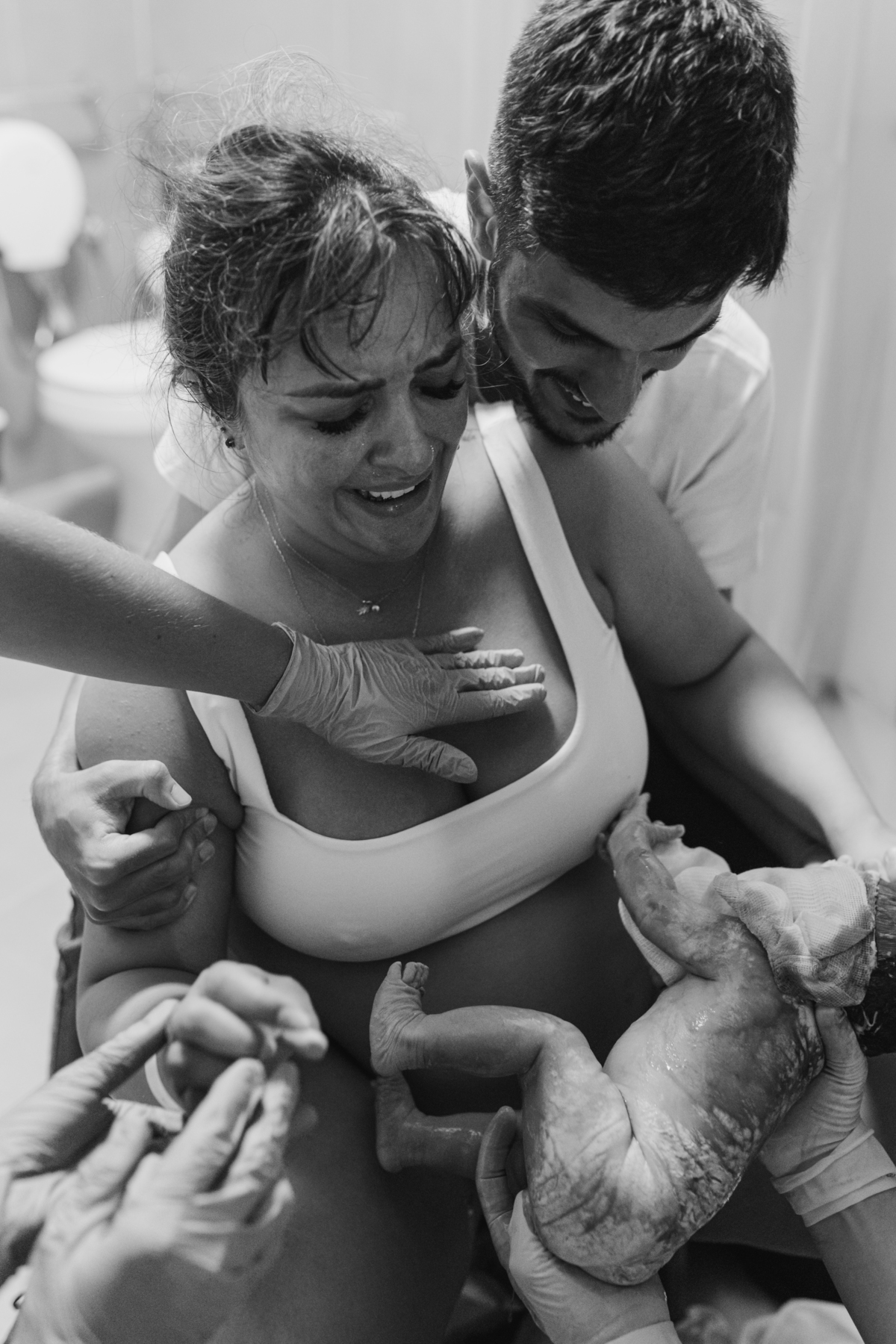 foto em preto e branco de bebê nascendo de parto normal e sorriso da mãe