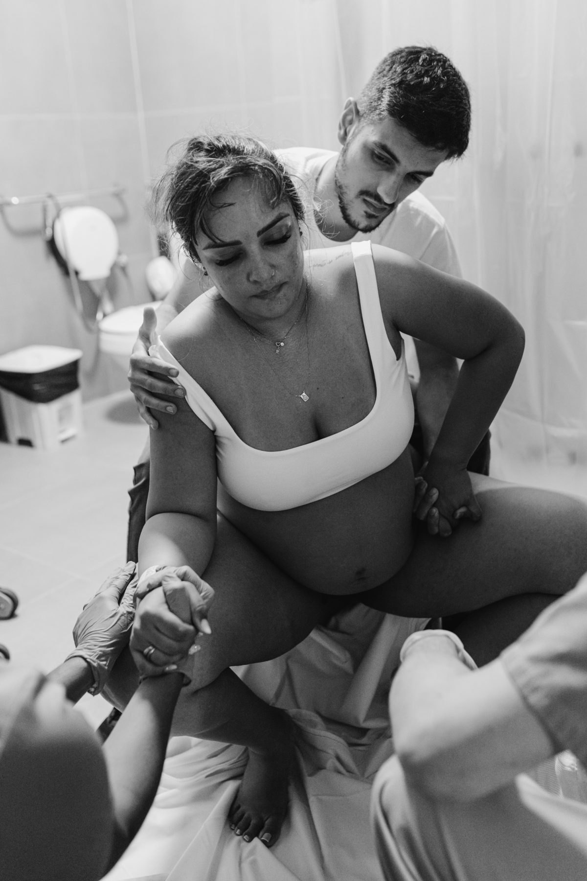 foto em preto e branco de gestante sentada em banquinho da sala de parto em período expulsivo