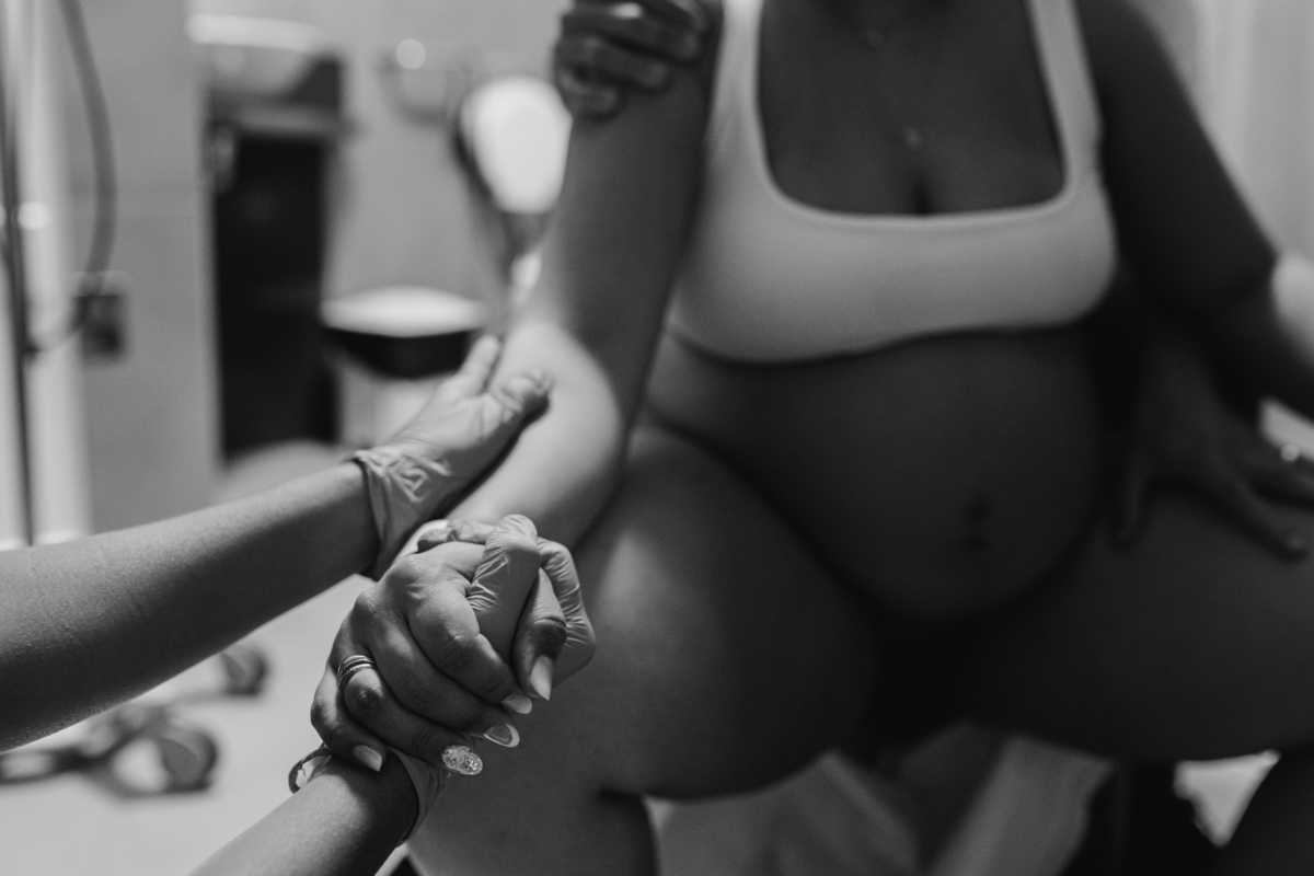 foto em preto e branco de doula segurando a mão da gestante que está em trabalho de parto