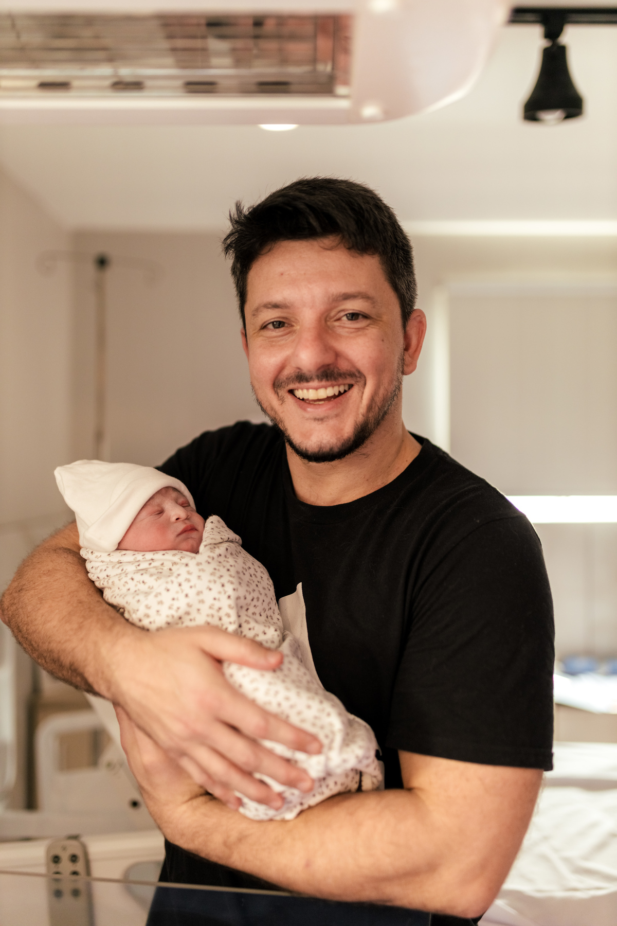 pai carregando o filho nos braços na maternidade