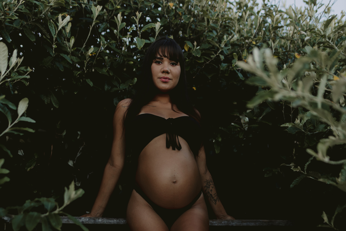 foto de gestante de biquíni tirada de baixo pra cima, com a gestante encarando a câmera