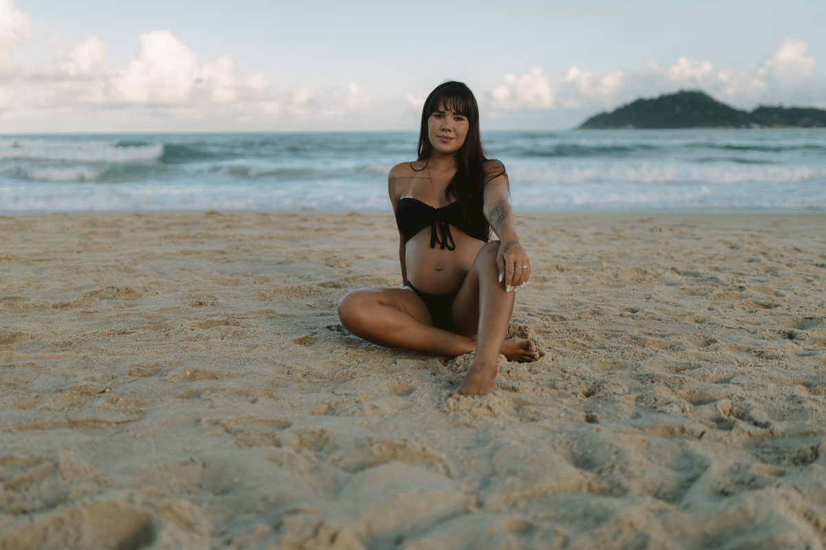 foto de gestante sentada na areia da praia