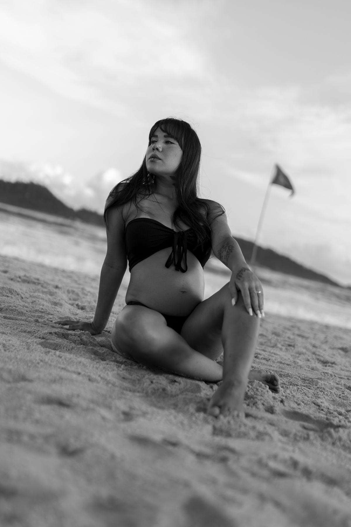 foto em preto e branco de gestante sentada na areia da praia