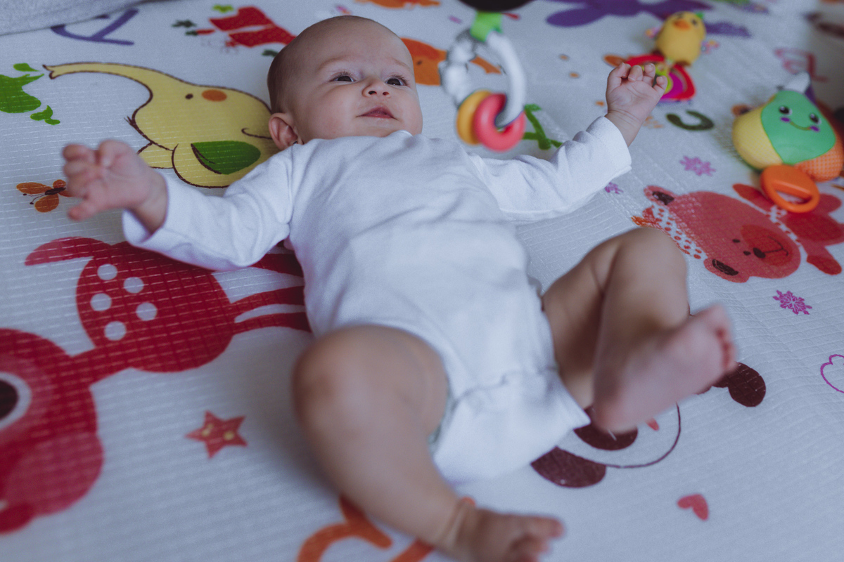 bebê brincando em seu tapete de brinquedos