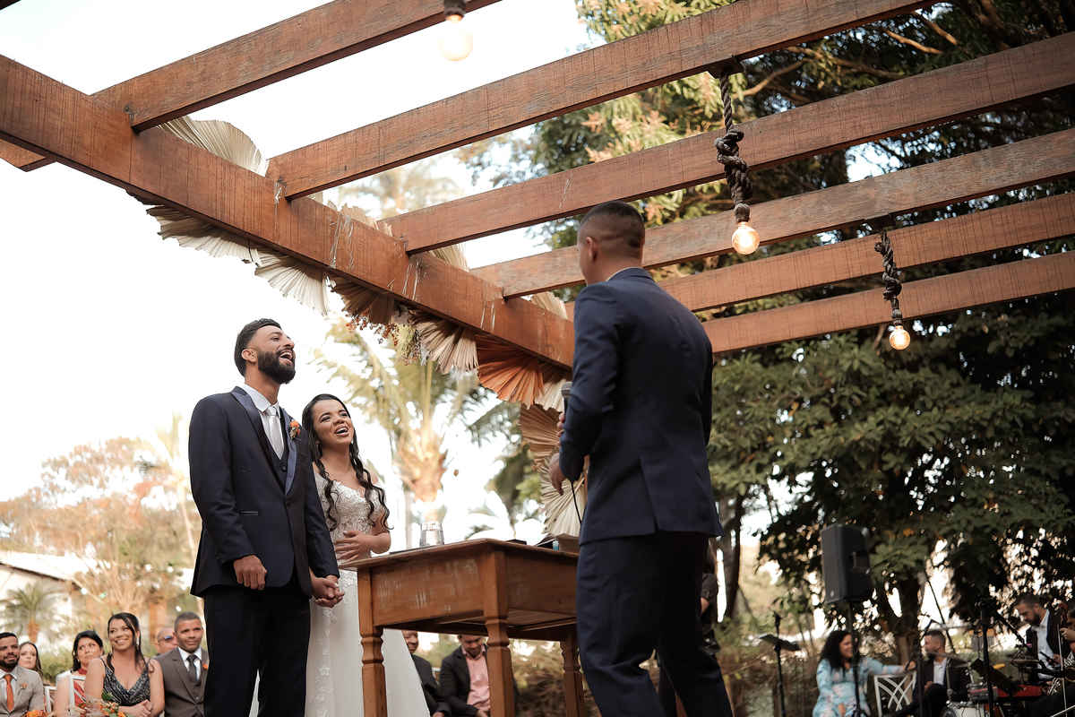 Momentos espontâneos dos noivos durante a cerimônia ao ar livre em Santa Luzia, Minas Gerais, mostrando a alegria e emoção do casamento.

