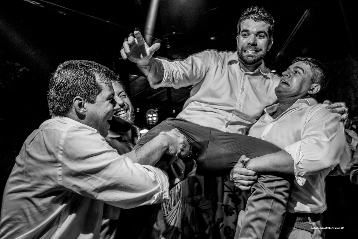 noivo sendo jogado para cima na festa de casamento