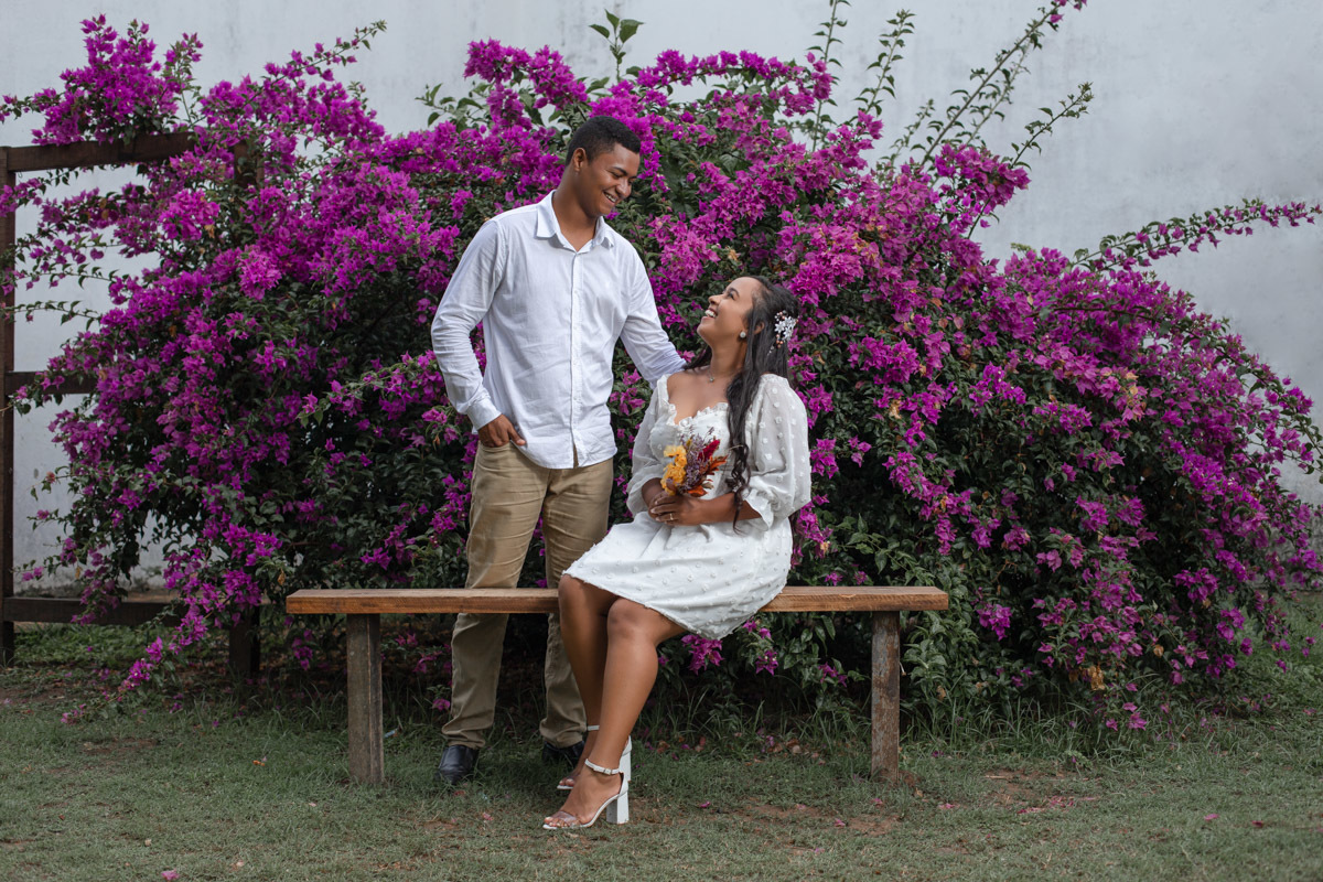 Noivos posando com Buquê da noiva em praça florida