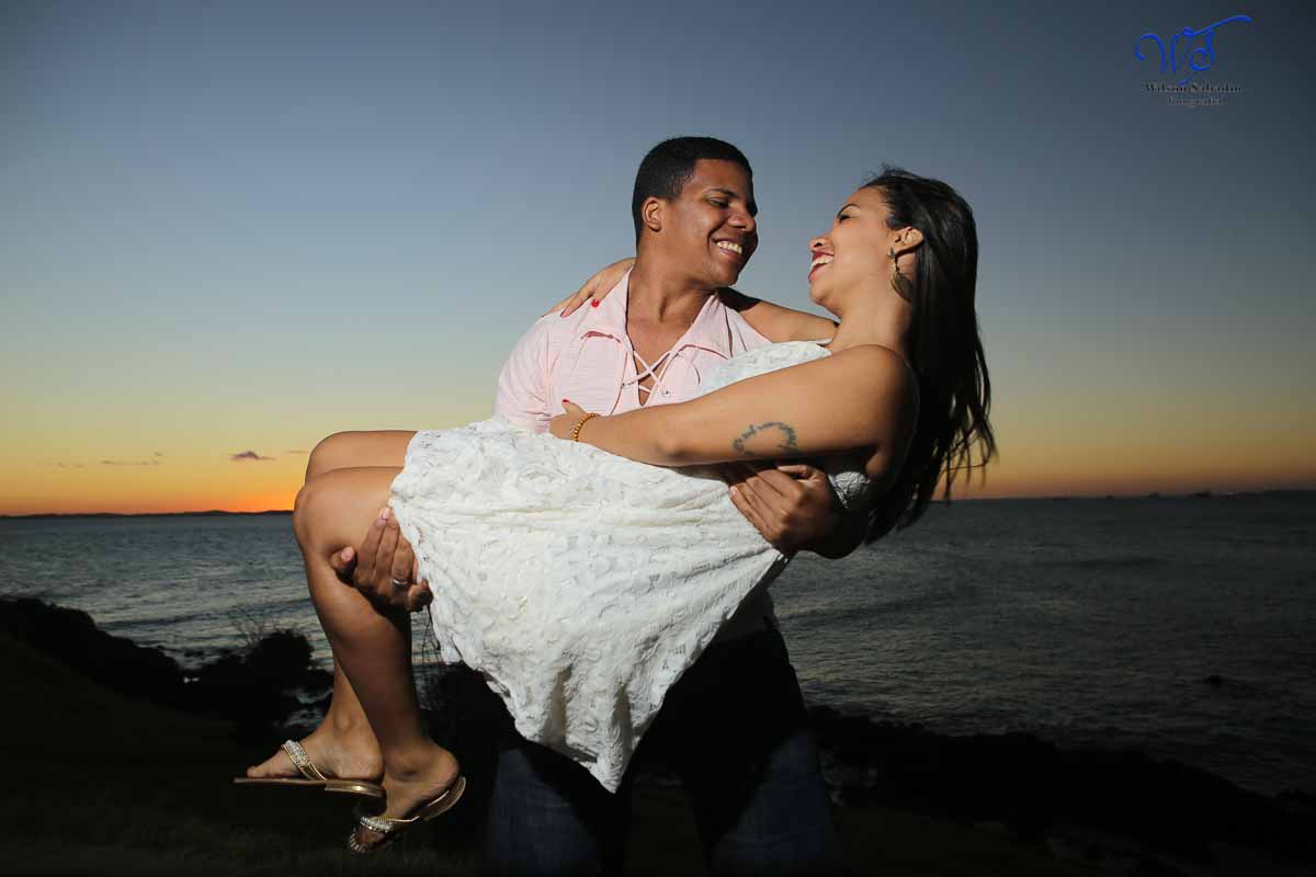 Ensaio de casal, o noivo carregando a noiva em um lindo pôr do sol