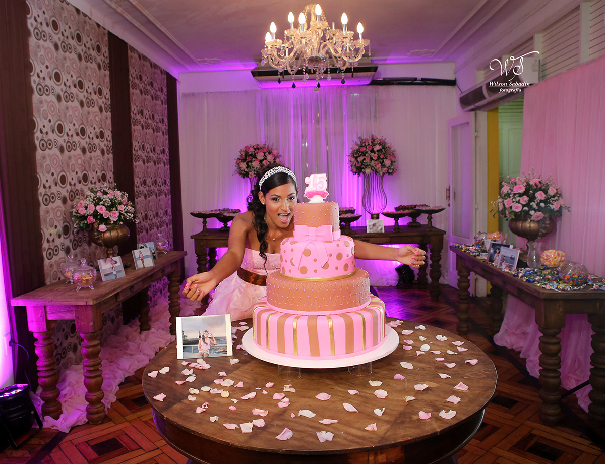 fotografia de 15 a debutante junto com o seu bolo de aniversário