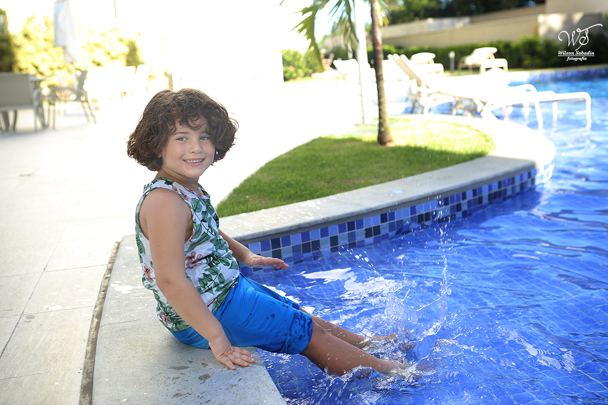 fotografia infantil em Salvador ba, o menino brincando na borda da piscina